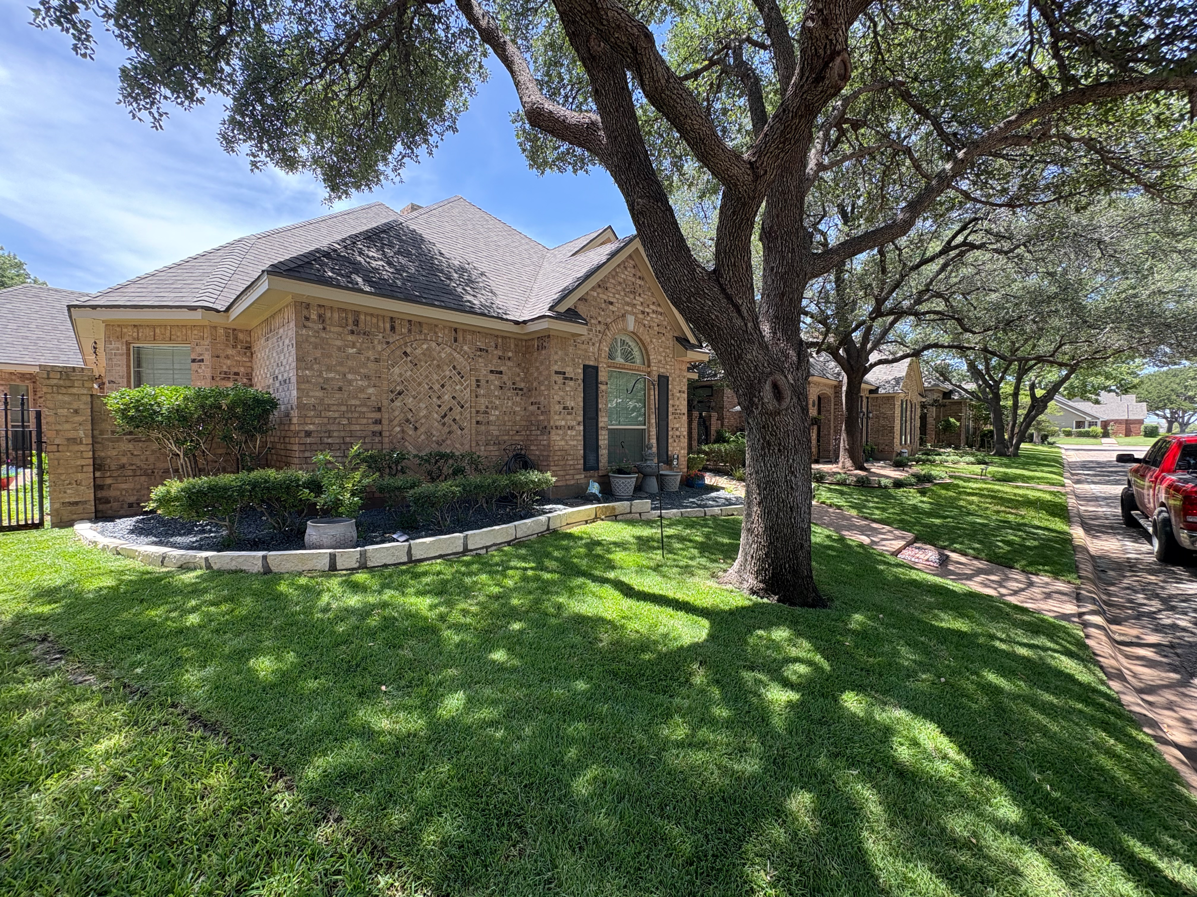 Maintained lawn and landscaping around a brick home